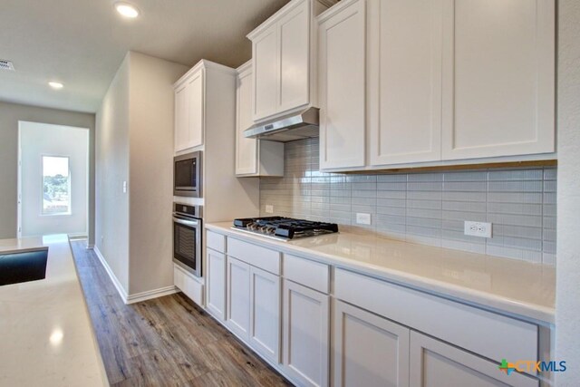 kitchen featuring tasteful backsplash, white cabinets, stainless steel appliances, and light hardwood / wood-style floors