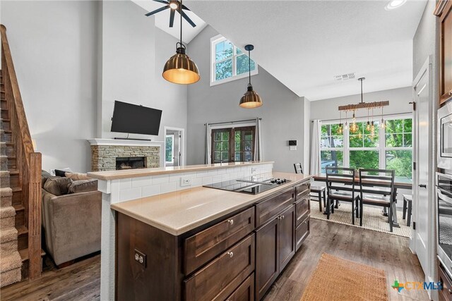4130 Cripple Creek Dr, Temple, TX 76502 - kitchen with black electric cooktop, light countertops, dark brown cabinets, a fireplace, and high vaulted ceiling