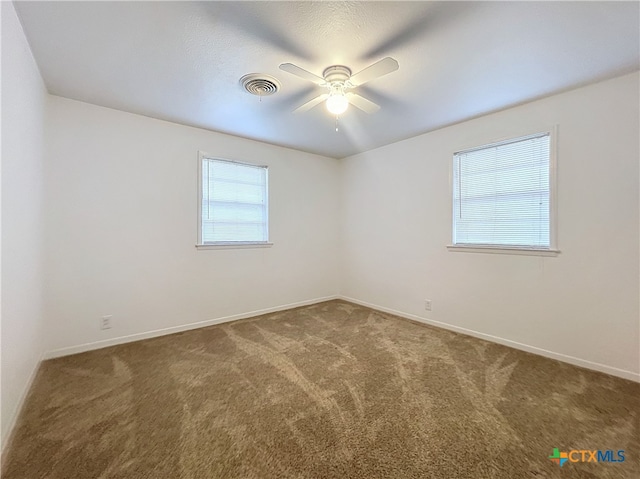 empty room featuring ceiling fan and dark carpet