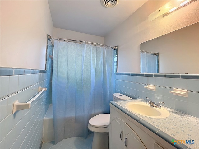 full bathroom featuring vanity, tile patterned flooring, toilet, shower / bathtub combination with curtain, and tile walls