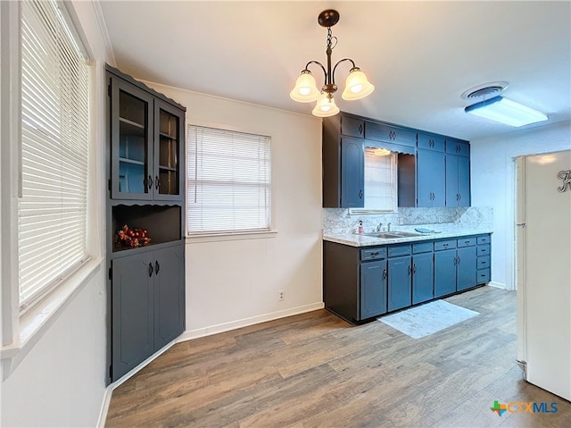 kitchen with white refrigerator, decorative light fixtures, light hardwood / wood-style flooring, decorative backsplash, and a notable chandelier