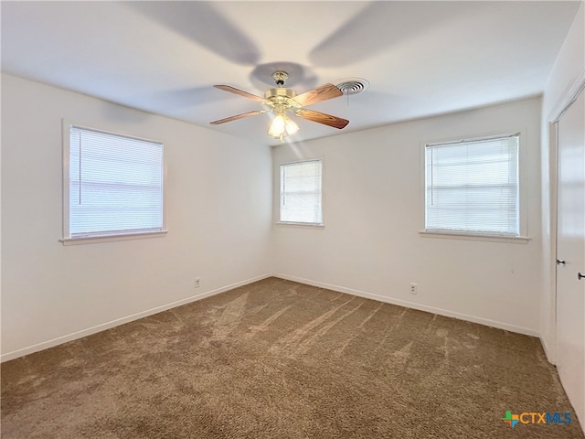 unfurnished room featuring dark carpet, plenty of natural light, and ceiling fan