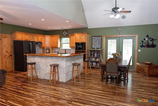 211 Cambridge Dr, New Braunfels, TX 78132 - kitchen with a kitchen breakfast bar, tasteful backsplash, ceiling fan, black appliances, and dark wood-style flooring