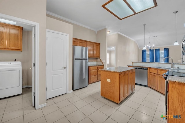 kitchen featuring light tile patterned floors, hanging light fixtures, stainless steel appliances, a center island, and washer / clothes dryer