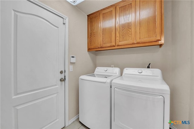 laundry room with light tile patterned flooring, cabinets, and washing machine and clothes dryer