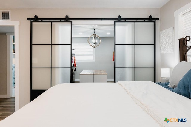 bedroom with a barn door, visible vents, and wood finished floors