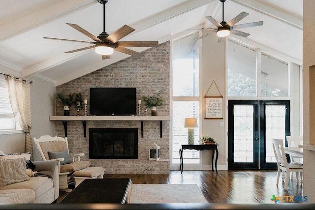 living area with wood finished floors, a fireplace, ceiling fan, and vaulted ceiling with beams