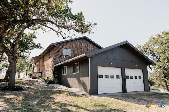 view of home's exterior with a garage, brick siding, and driveway