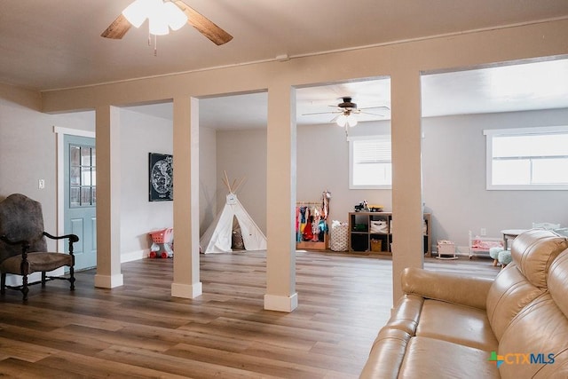 living area featuring baseboards, ceiling fan, and wood finished floors