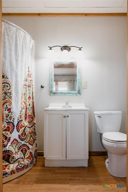 bathroom featuring toilet, a shower with shower curtain, wood finished floors, and vanity