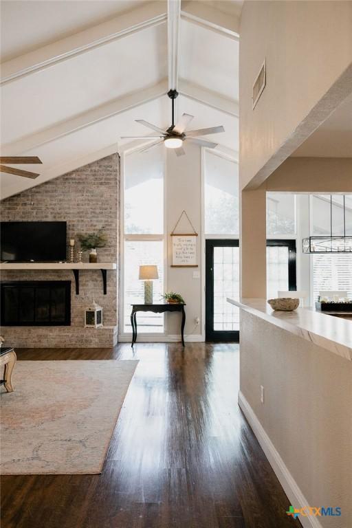 living room featuring ceiling fan, a brick fireplace, and lofted ceiling with beams