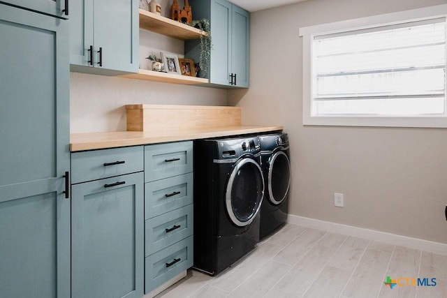 washroom featuring cabinet space, washer and dryer, and baseboards