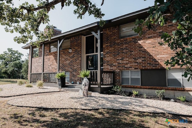exterior space with a chimney and brick siding
