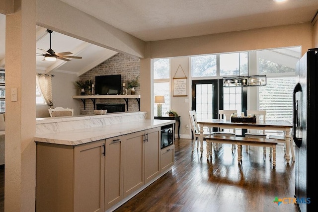 kitchen with a wealth of natural light, dark wood-type flooring, black appliances, and vaulted ceiling with beams
