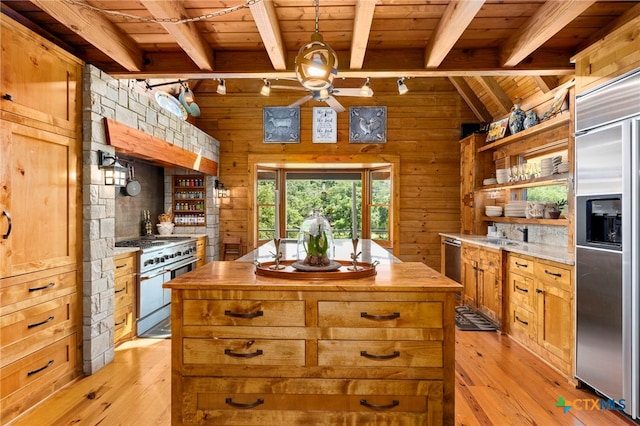 kitchen with light wood-type flooring, wooden walls, and high end appliances