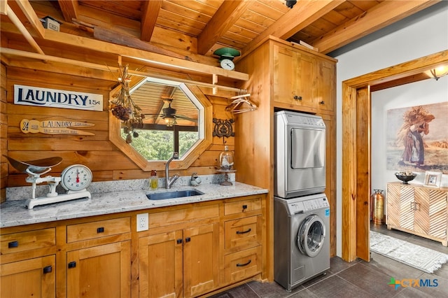 kitchen with stacked washer / dryer, light stone counters, wood ceiling, sink, and beamed ceiling