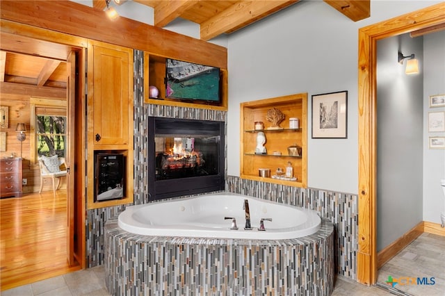 bathroom featuring a multi sided fireplace, wood ceiling, tile patterned floors, and beam ceiling