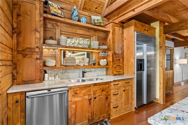 kitchen featuring stainless steel appliances, sink, light stone counters, beam ceiling, and wood ceiling