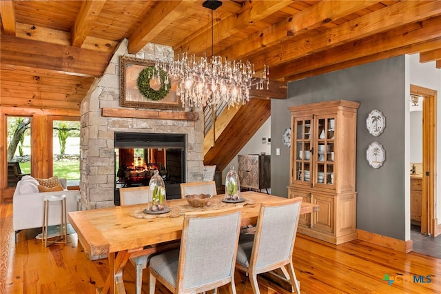 dining area featuring a fireplace, light hardwood / wood-style floors, beamed ceiling, and wood ceiling