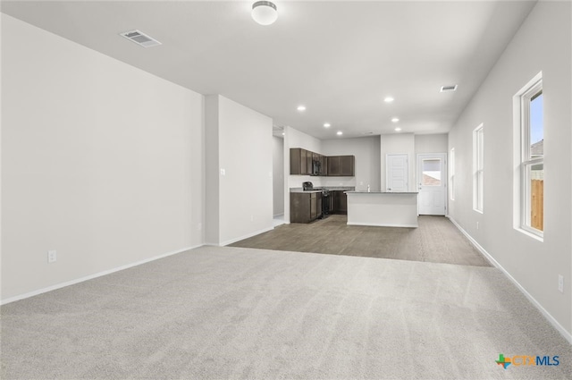 unfurnished living room with light colored carpet and plenty of natural light