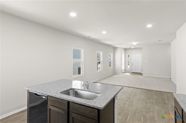 kitchen with light stone countertops, a kitchen island with sink, sink, dishwasher, and light hardwood / wood-style floors