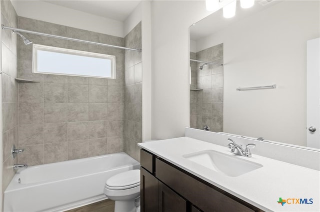 full bathroom featuring hardwood / wood-style flooring, tiled shower / bath combo, toilet, and vanity