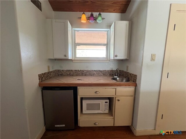 184 Guadalupe Hills Ln, Seguin, TX 78155 - kitchen with white microwave, dishwasher, tile counters, white cabinets, and refrigerator