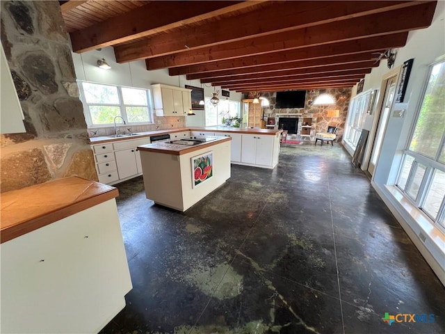 184 Guadalupe Hills Ln, Seguin, TX 78155 - kitchen with beamed ceiling, a fireplace, white cabinets, open floor plan, and a center island