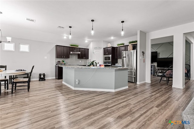 kitchen with dark brown cabinets, stainless steel appliances, an island with sink, and light hardwood / wood-style flooring