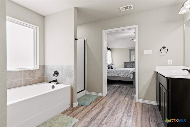 bathroom with ceiling fan, plus walk in shower, wood-type flooring, and vanity