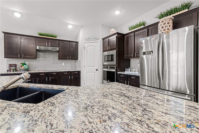 kitchen featuring backsplash, stainless steel appliances, light stone counters, and lofted ceiling