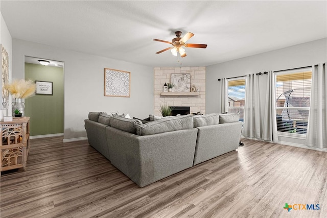 living room with hardwood / wood-style flooring, ceiling fan, and a fireplace