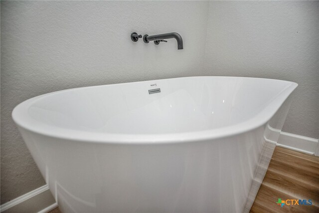 details with hardwood / wood-style flooring and a bathing tub