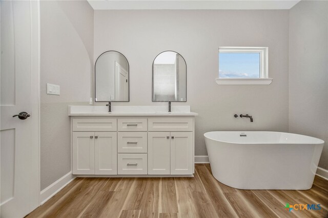 bathroom with a tub to relax in, vanity, and hardwood / wood-style floors