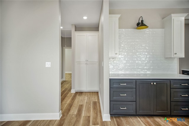 kitchen with tasteful backsplash, white cabinetry, and light hardwood / wood-style floors