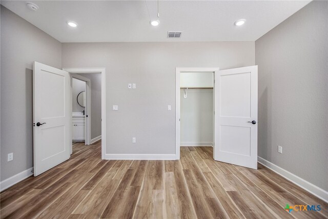 unfurnished bedroom with hardwood / wood-style flooring, a walk in closet, and a closet