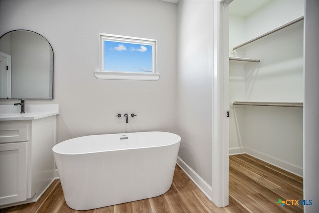 bathroom featuring hardwood / wood-style floors, a bath, and vanity