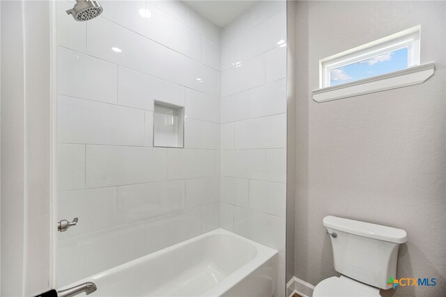 bathroom featuring toilet and tiled shower / bath