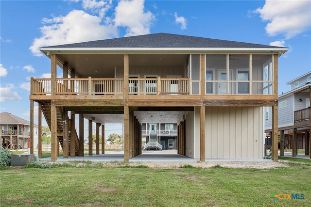 rear view of house featuring a lawn, a sunroom, and a patio area