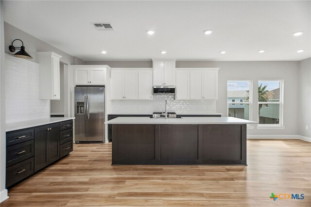 kitchen with white cabinetry, decorative backsplash, appliances with stainless steel finishes, and light hardwood / wood-style floors