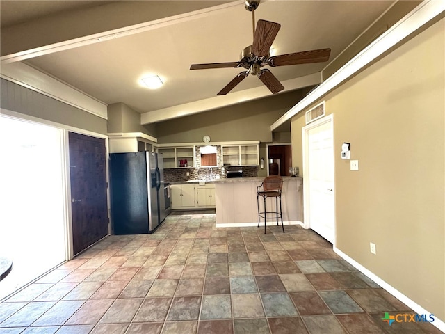 kitchen featuring stainless steel fridge, white cabinetry, plenty of natural light, and vaulted ceiling