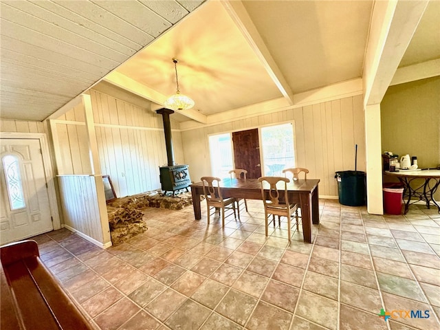 dining space featuring wood walls, tile patterned floors, and a wood stove