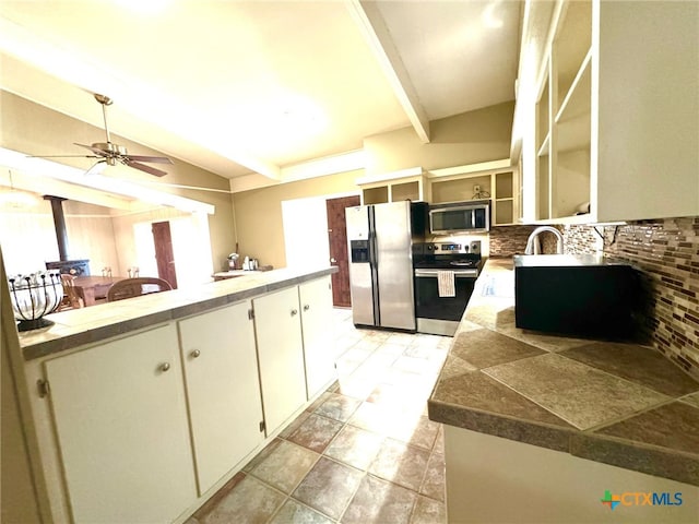 kitchen featuring vaulted ceiling with beams, sink, tasteful backsplash, ceiling fan, and appliances with stainless steel finishes