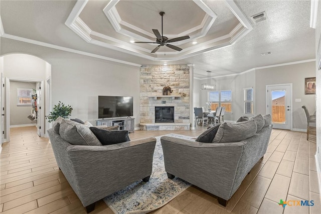 living room with visible vents, a tray ceiling, arched walkways, and crown molding