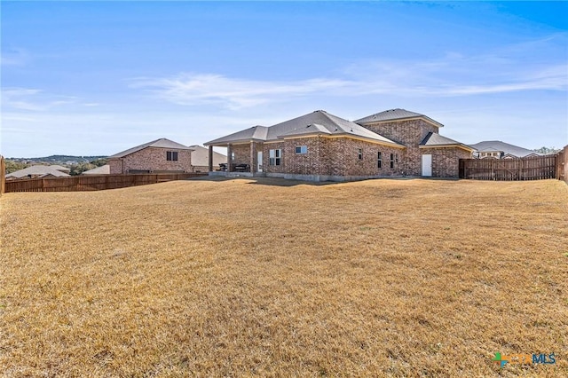 back of house featuring fence, a lawn, and brick siding