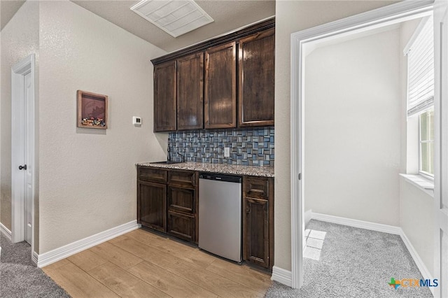 bar featuring dishwashing machine, visible vents, baseboards, backsplash, and light wood finished floors