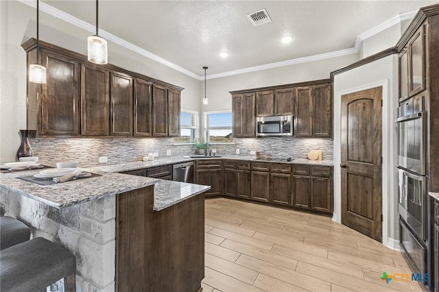 kitchen with appliances with stainless steel finishes, visible vents, dark brown cabinetry, and a peninsula