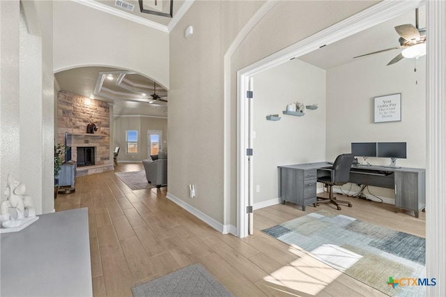 entryway with arched walkways, coffered ceiling, a fireplace, wood finished floors, and a ceiling fan