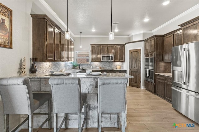 kitchen with stainless steel appliances, light wood-style floors, dark brown cabinetry, a sink, and light stone countertops