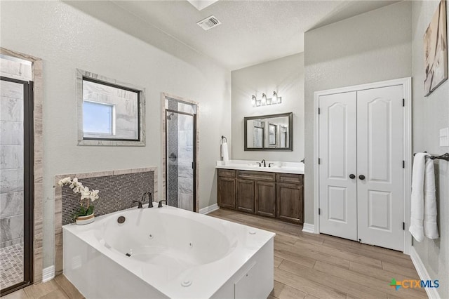 full bath featuring a stall shower, visible vents, wood finished floors, a jetted tub, and vanity